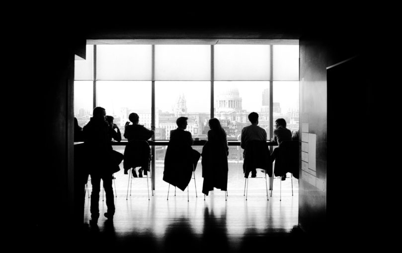 black and white photo people sitting in office with view of washington dc